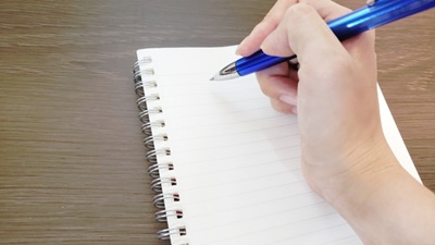 ノートにペンで書こうとしている手の画像